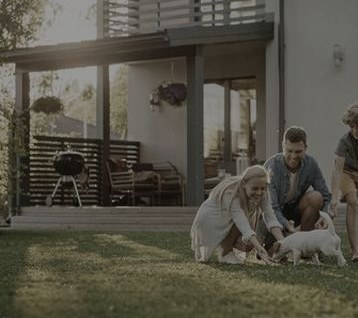A long-time homeowner and his family with their dog in the backyard, beside a covered patio