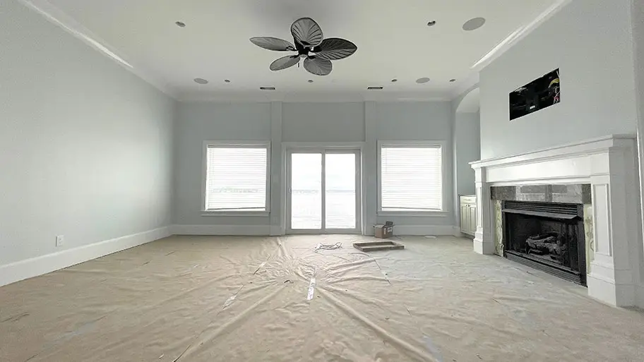 Living room prepared for painting with furniture removed and flooring fully covered in Hampton Roads home